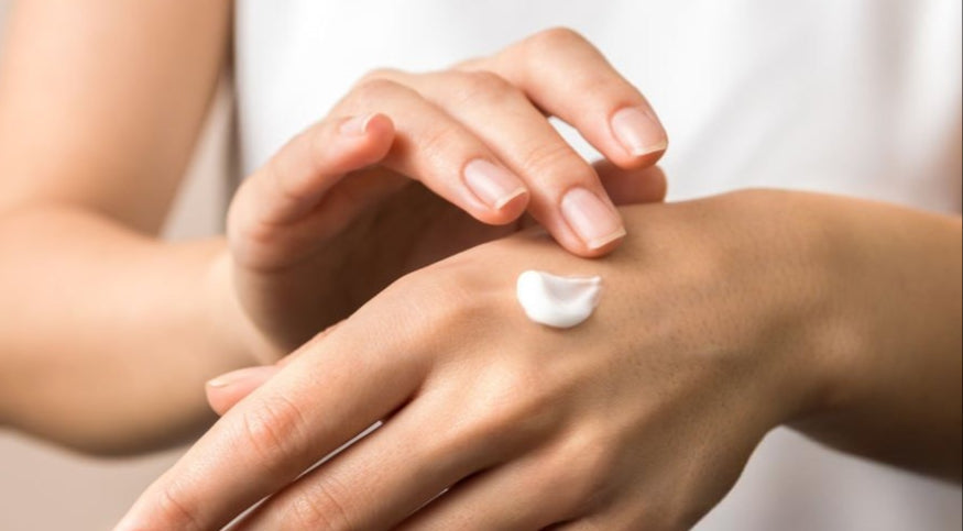 Person applying cream to their hand with a blurred background