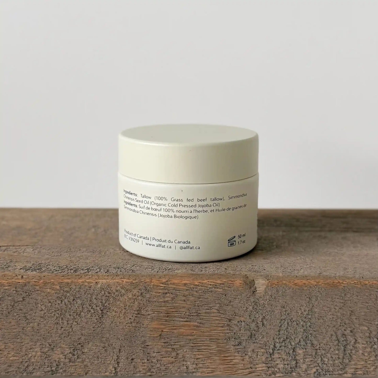 allfat tallow cream jar with text on a wooden surface and light gray background