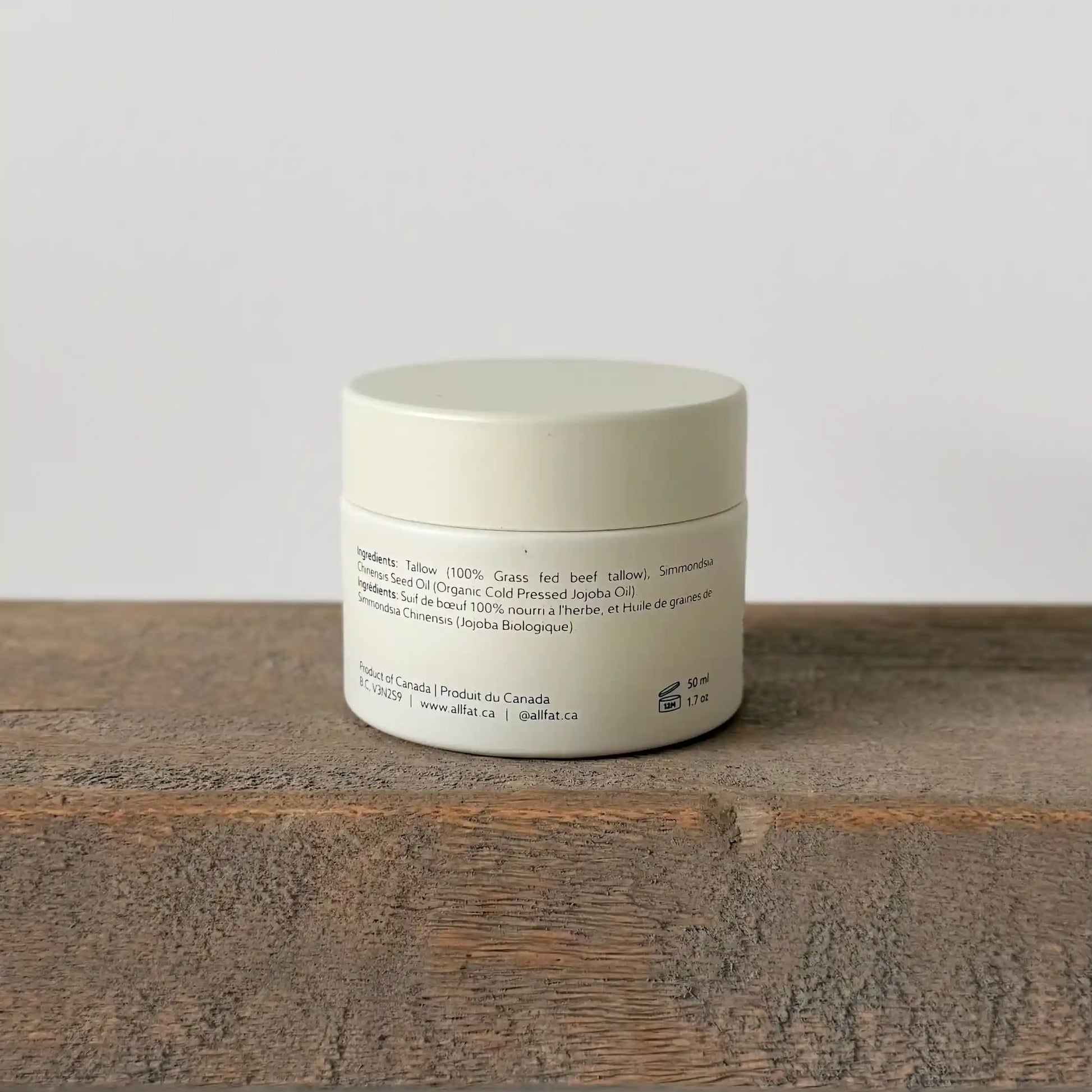 allfat tallow cream jar with text on a wooden surface and light gray background