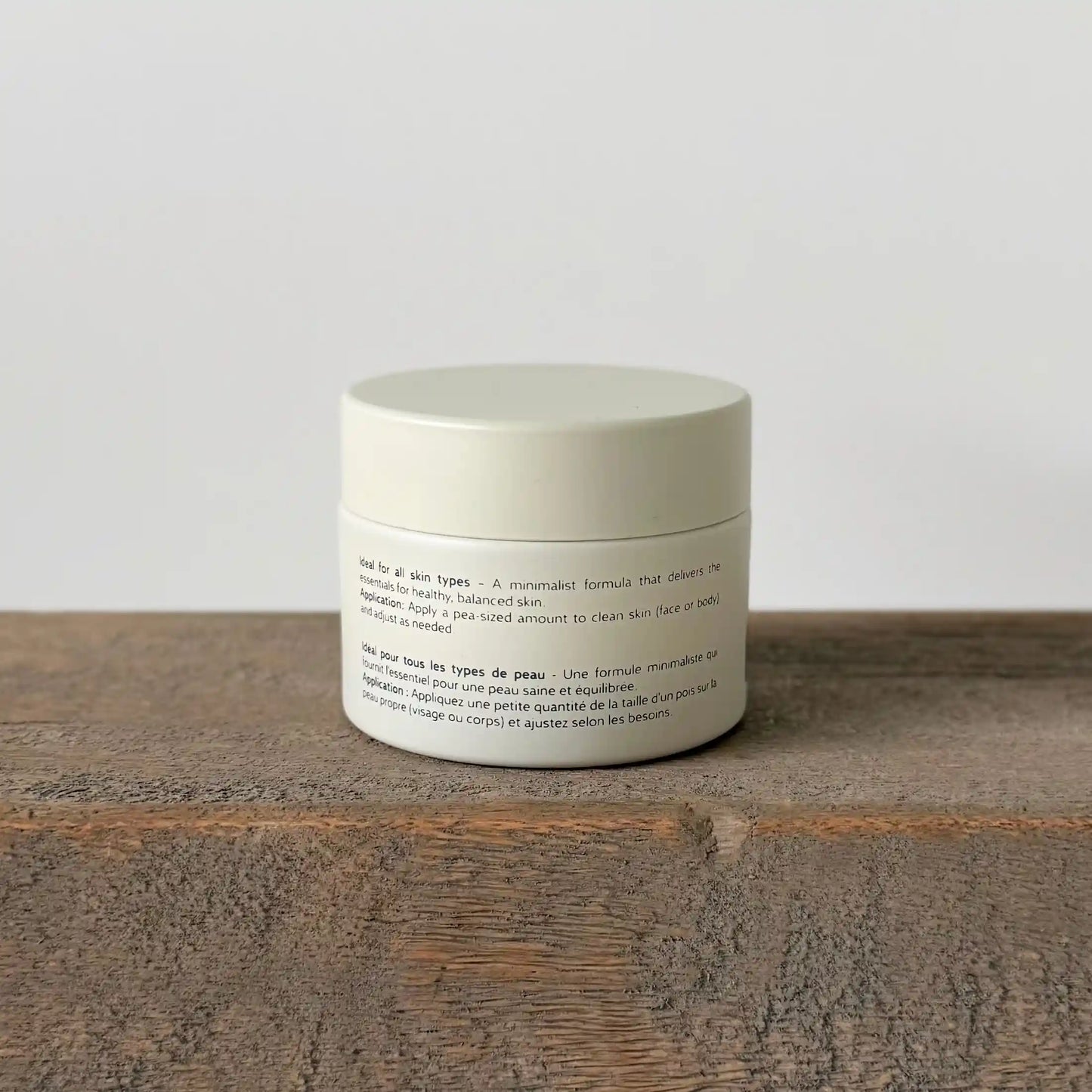 White ceramic jar of allfat tallow cream with text on a wooden surface and light gray background