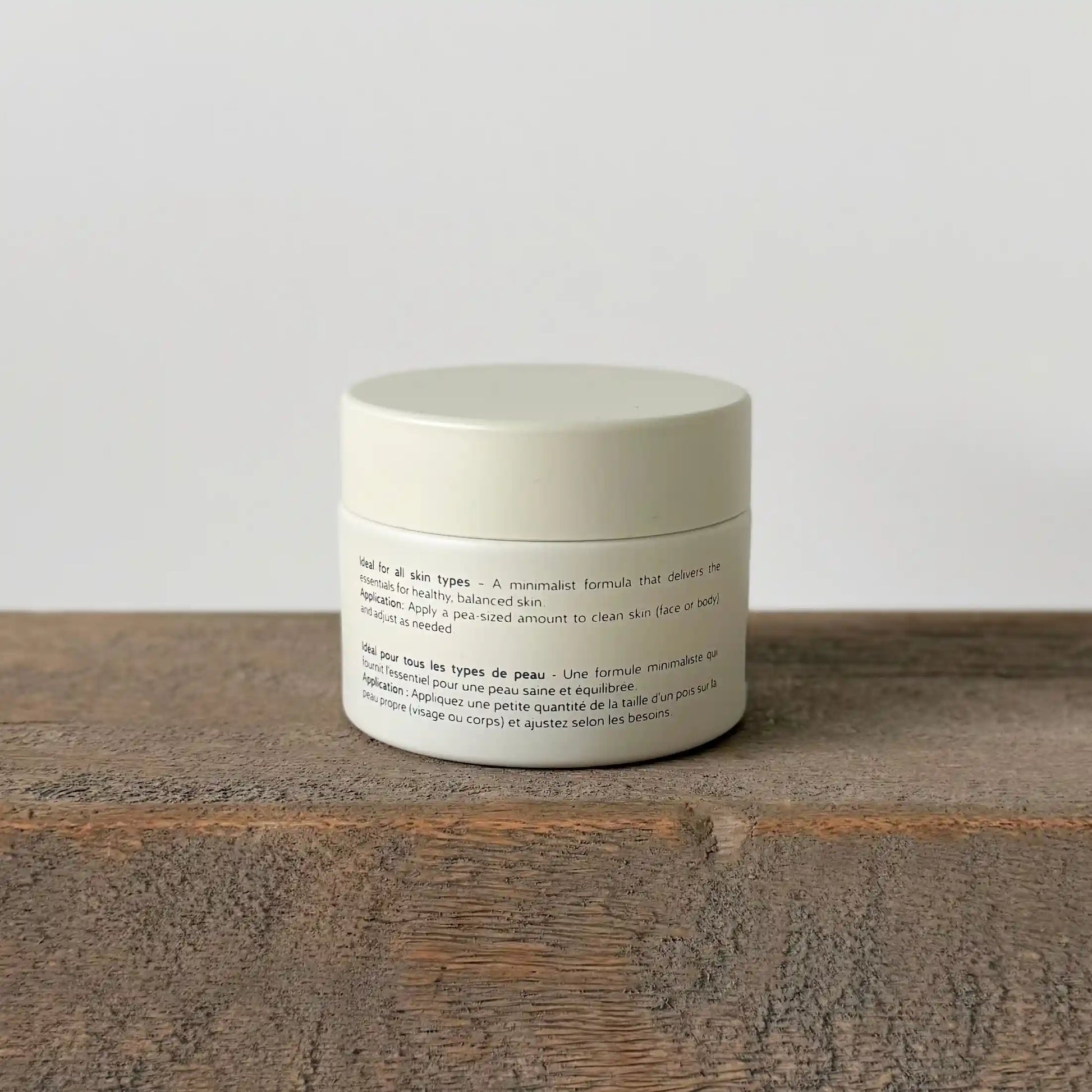 White ceramic jar of allfat tallow cream with text on a wooden surface and light gray background