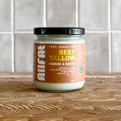Jar of beef tallow on a wooden surface with a tiled wall background