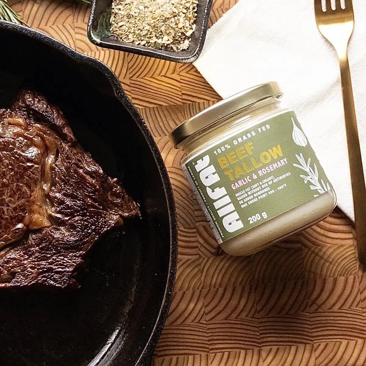 Jar of garlic rosemary beef tallow with a cooked steak on a wooden surface