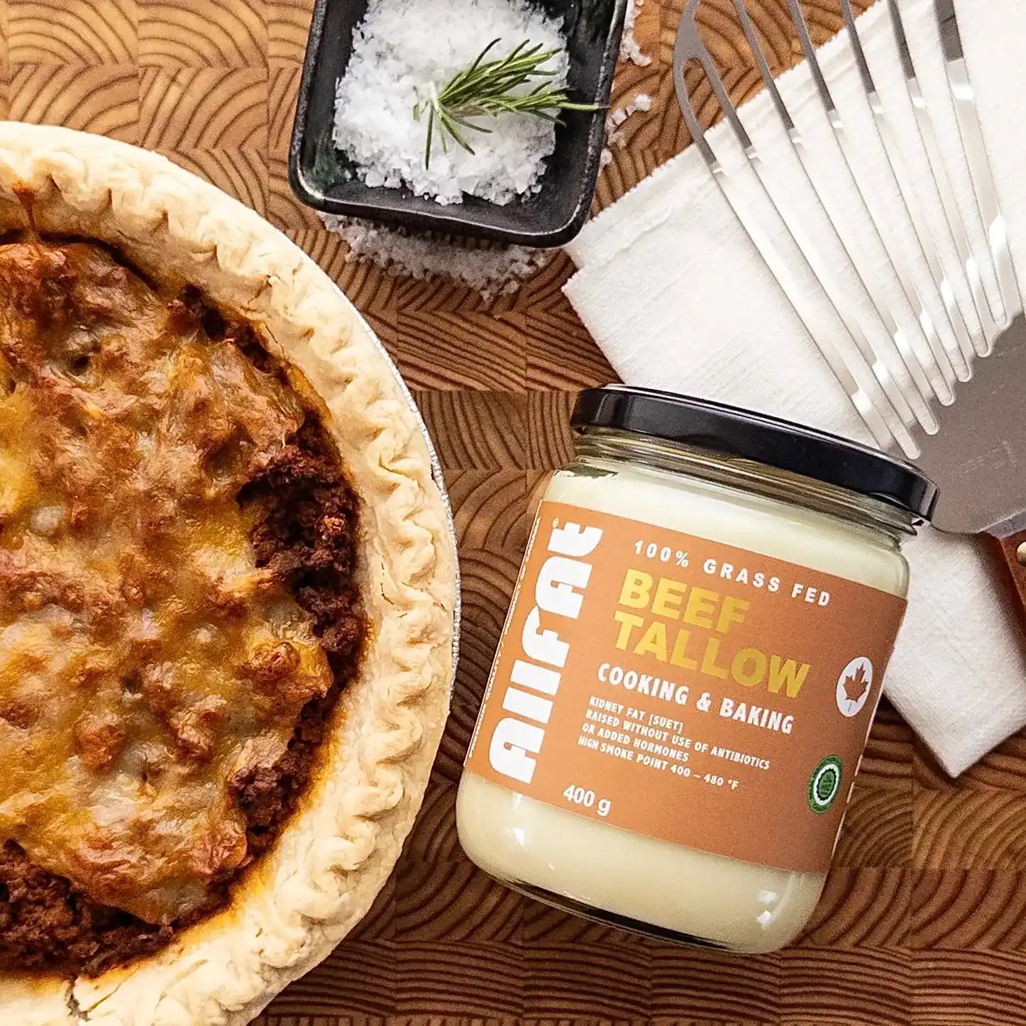 Pie with a jar of canadian beef tallow on a wooden surface