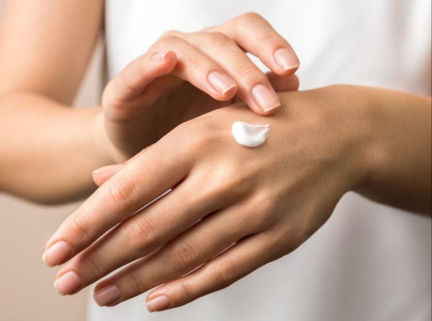 Person applying cream to their hand with a blurred background