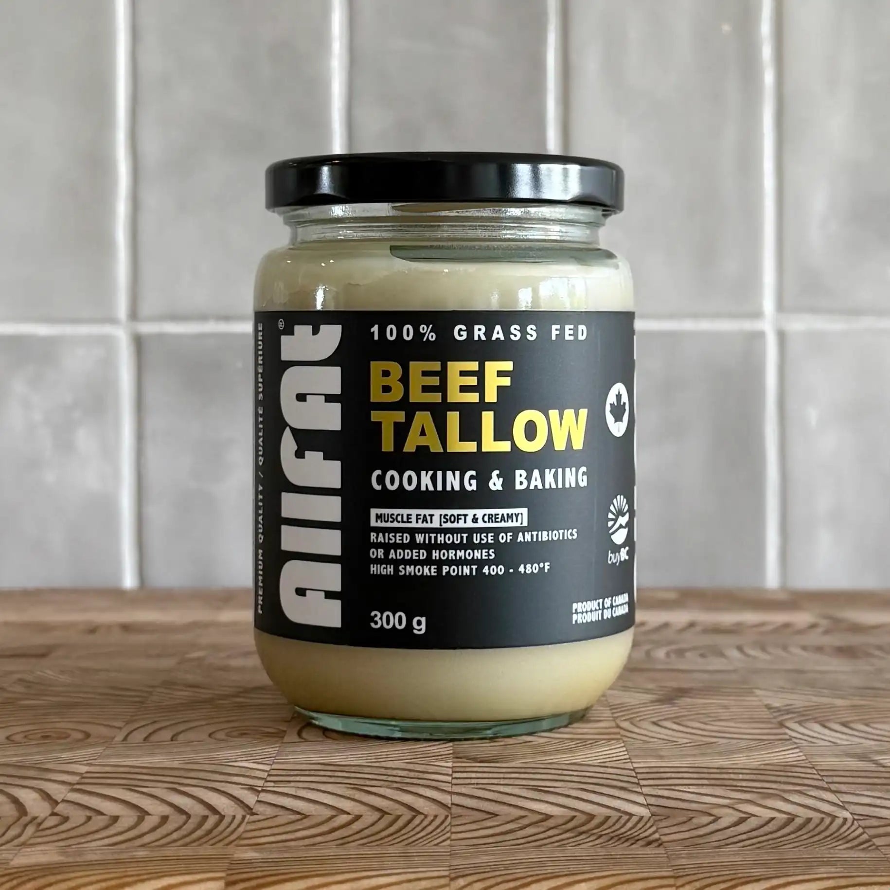 Jar of beef tallow on a wooden surface with a tiled wall background