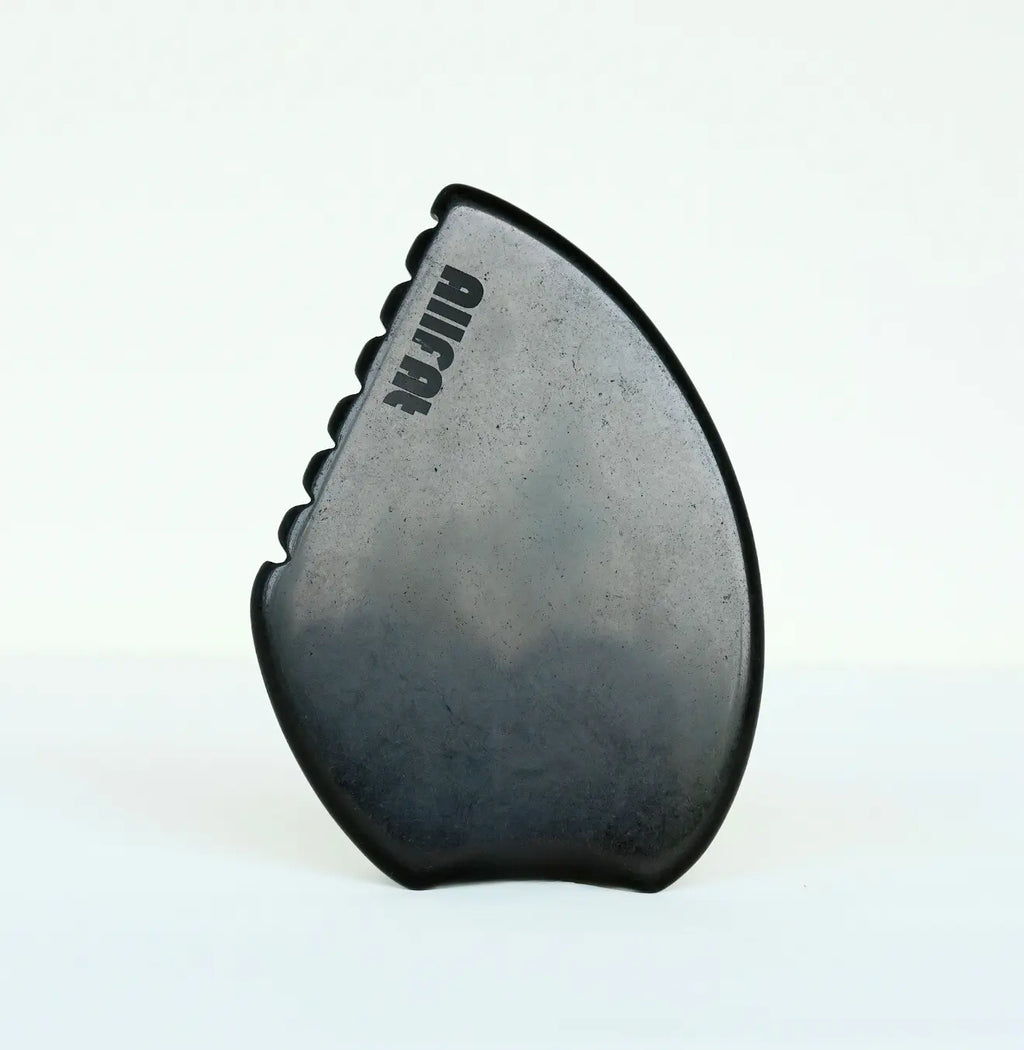 black obsidian gua sha tool against a white background