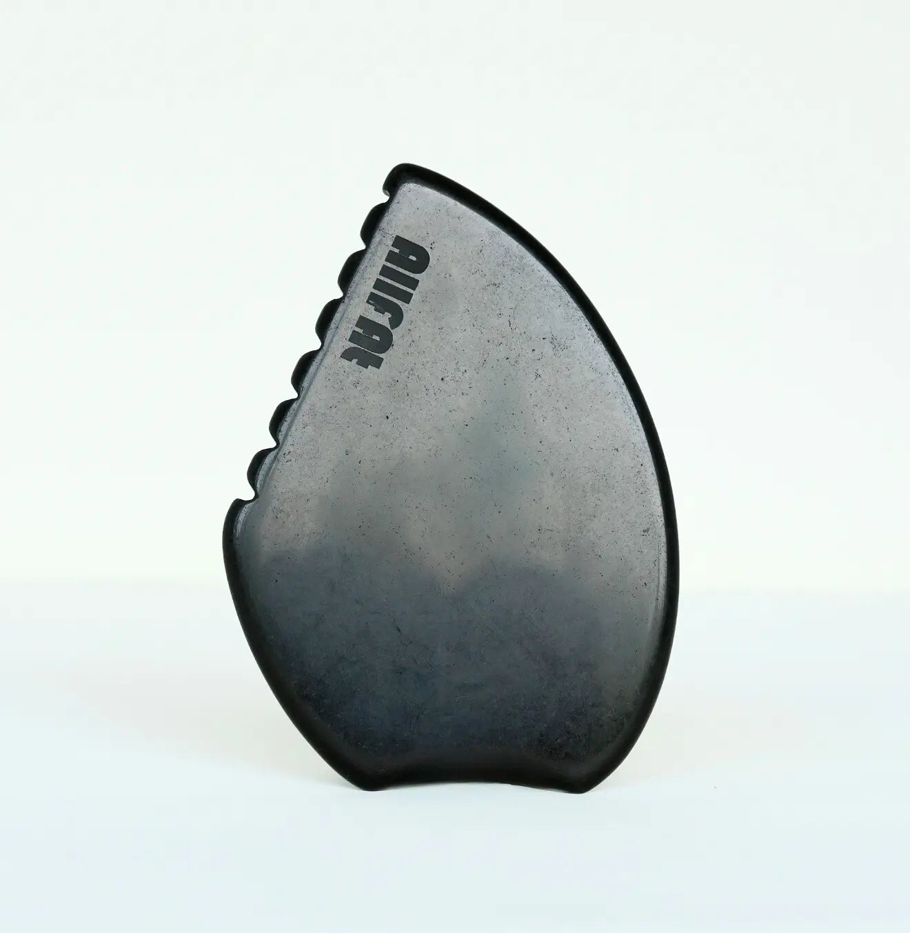 black obsidian gua sha tool against a white background