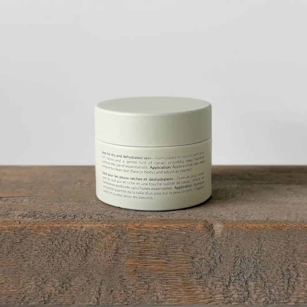 Ceramic tallow cream jar with text on a wooden surface and light gray background