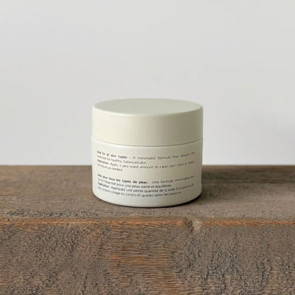 White ceramic jar of allfat tallow cream with text on a wooden surface and light gray background