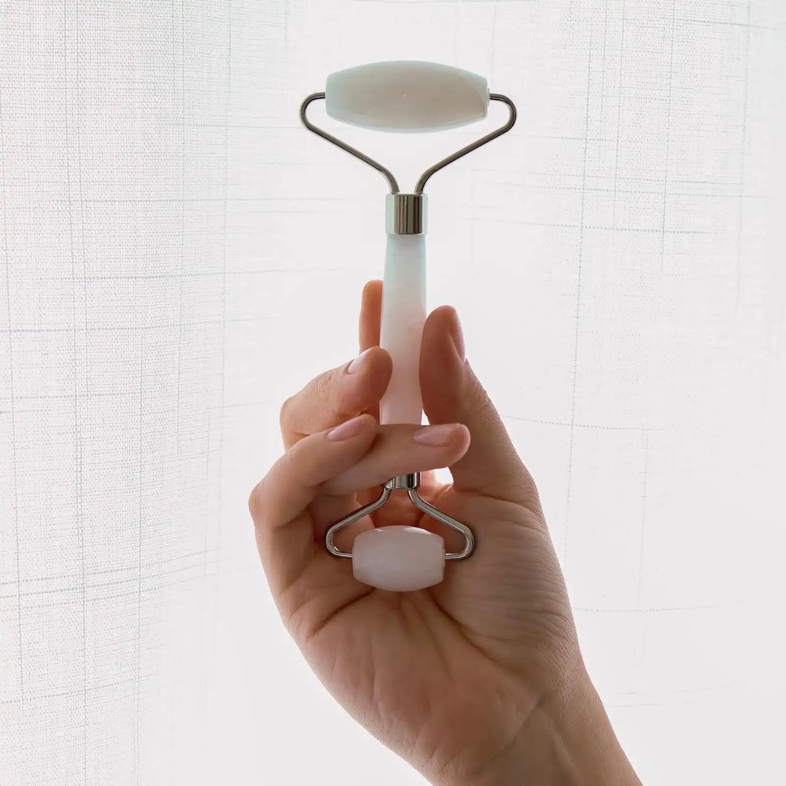 Hand holding a white derma roller against a light background