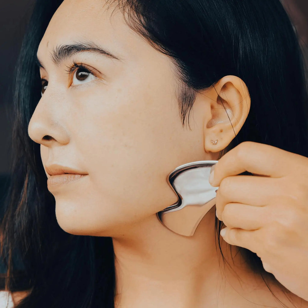 Close-up of a person using an ear cleaning tool on their jawline and skin.