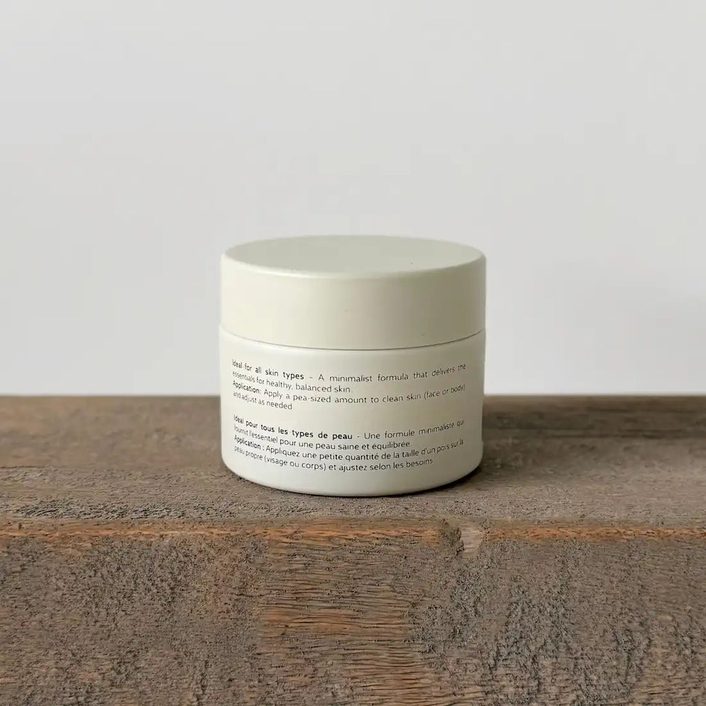 White tallow cream jar with text on a wooden surface and light gray background