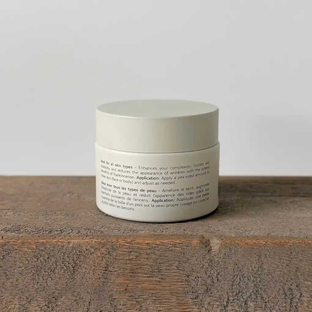 White ceramic tallow cream jar with text on a wooden surface